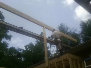 Carpenter setting a ridge beam over a new addition frame — Ice Dam Removal by Roofing Brothers in Bokchito