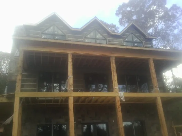 Dormers and porch framing on a large log home under construction — Roof Coating work by our crew in Bokchito