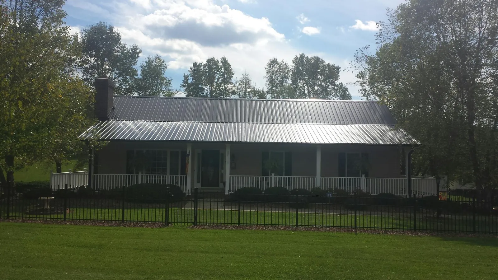 Gray metal roof on a brick ranch with a full width front porch — Gutter Guard Installation work by our crew in Bokchito