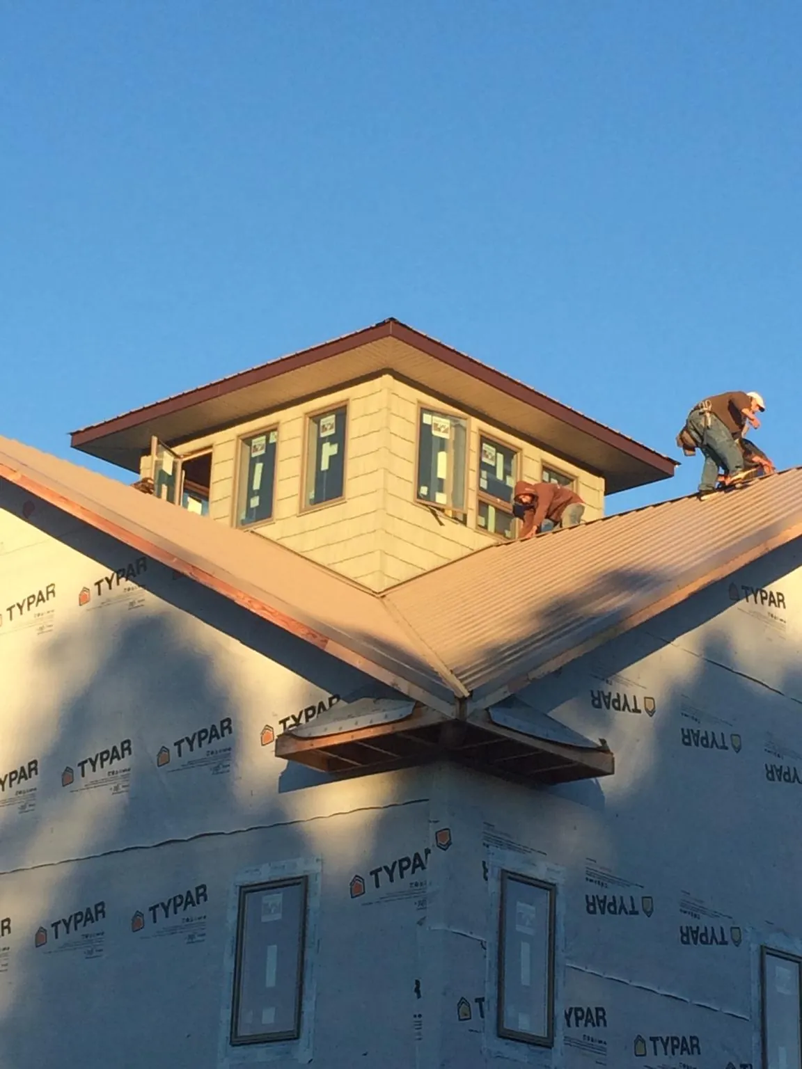 Roofers working around a rooftop cupola on a new metal roof at sunset — Roof Waterproofing in Bokchito by Roofing Brothers